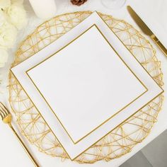 a place setting with white and gold plates, silverware and flowers on the table