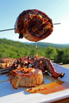 the meat is being grilled on the grill with skewers in front of it