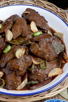 a white plate topped with meat and onions covered in sauce on top of a table