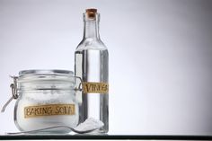 an empty glass bottle with baking soda in it and a salt shaker next to it