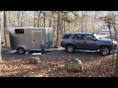 a man standing next to a trailer in the woods with a child looking at it