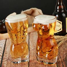 two glasses filled with beer sitting on top of a wooden table