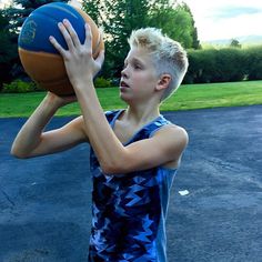 a young boy holding a basketball up to his face