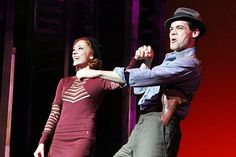 a man and woman are dancing on stage with one holding the other's hand