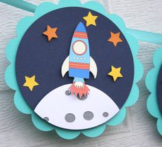 a paper rocket ship on top of a blue and white card with stars around it