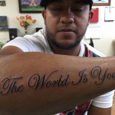 a man with a tattoo on his arm that says the world is yours