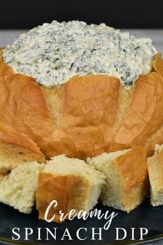 spinach dip in bread on a plate with the words creamy spinach dip above it