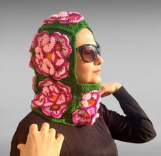 a woman wearing a crocheted hat with flowers on it's head and scarf around her neck