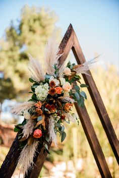 Modern triangle wedding ceremony arch with boho inspired wedding flowers in burnt ochre and blush. Fall wedding decor Boho Wedding Triangle Arch, Boho Floral Arch Wedding, Fall Wedding Triangle Arch, Boho Arbor Floral Arrangement, Wedding 2023 Decor, Fall Triangle Arch, Boho Isle Wedding, November Wedding Arch, Diy Boho Wedding Arch Flowers