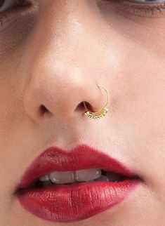 a woman with red lipstick and gold nose ring