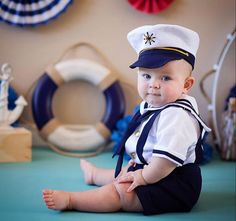 a baby in a sailor outfit sitting on the floor