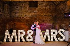 a newly married couple standing in front of the mr and mrs sign at their wedding