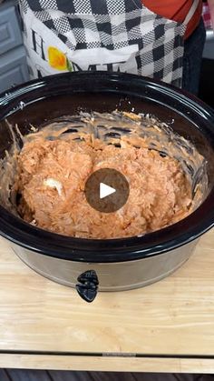 a slow cooker filled with food sitting on top of a wooden table