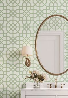 a bathroom with green and white wallpaper and a round mirror