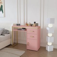 a pink desk with drawers in a white room next to a bed and painting on the wall