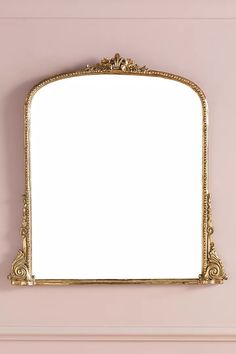 an ornate gold framed mirror on a pink wall