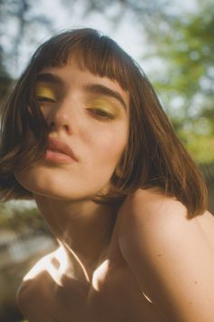 a woman with long brown hair and yellow eyeshadow is posing for the camera