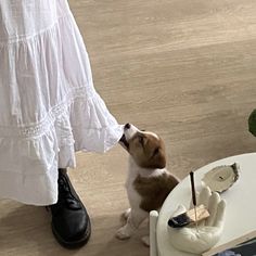 a dog sitting on the floor next to a woman's legs and holding an umbrella