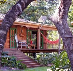 a small wooden cabin with a hammock on the porch