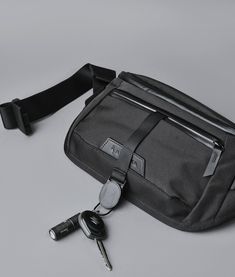 a black fanny bag with two keys attached to it