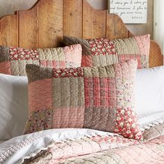 a bed topped with pillows and blankets next to a wooden headboard