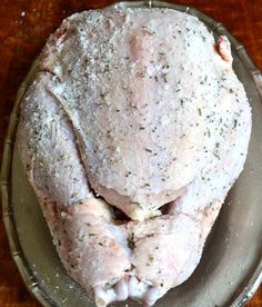 a raw chicken sitting on top of a glass plate covered in powdered sugar and seasoning