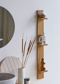 a wooden shelf that has some bottles on top of it next to a mirror and vase