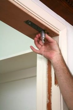 a man is holding an object in his hand while he fixes the door handle