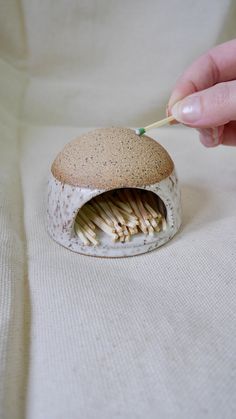 a person holding a toothbrush in their mouth next to a piece of food on a white surface