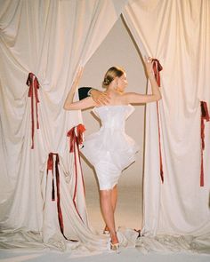 a woman standing in front of curtains with her arms up