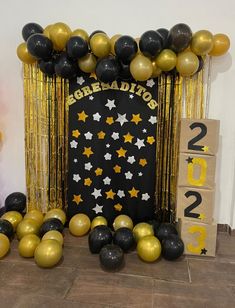 a black and gold backdrop with stars, balloons and streamers for a new year's eve celebration