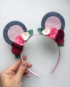 a person is holding up a mickey mouse ears headband with flowers on the side