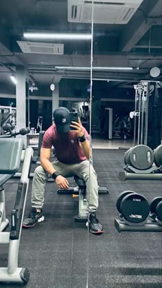 a man squatting on a bench in the middle of a gym with other equipment