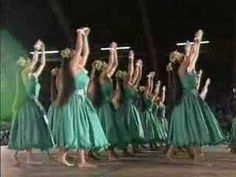 a group of women in green dresses dancing on stage with one holding up two swords