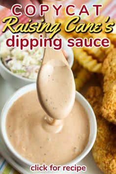 a spoon full of dipping sauce next to some fried chicken wings and coleslaw