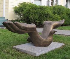 a bronze sculpture in the shape of a hand reaching out to touch someone's foot