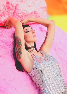 a woman laying on the ground next to a pink rock with her arms behind her head