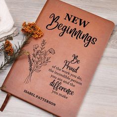 a new beginnings book sitting on top of a wooden table next to some dried flowers