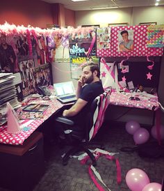 a man is sitting at his desk with balloons and streamers all over the room