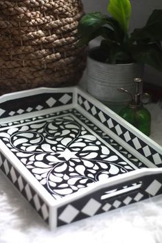 a black and white tray sitting on top of a table next to a potted plant