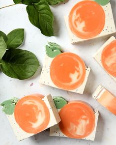 four pieces of soap with orange and white designs on them sitting next to green leaves