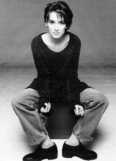 black and white photograph of a woman sitting on the floor with her hands in her pockets