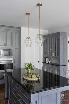 a large kitchen with an island in the middle and two lights hanging from the ceiling