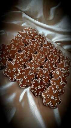 a bunch of cookies that are sitting on a table cloth with white flowers in the middle