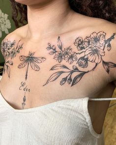 a woman with flowers and dragonflies tattoo on her chest is looking at the camera