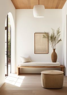 a living room with a couch, ottoman and plant on the wall next to it