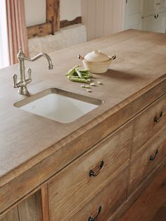 a kitchen sink sitting on top of a wooden counter next to a bowl of green beans