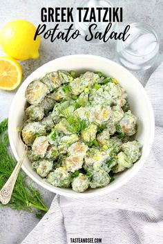 a white bowl filled with potato salad next to lemons and water on the side