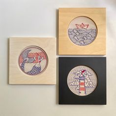 three wooden coasters with designs on them sitting next to each other in front of a white wall