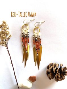 red - tailed hawk earrings with seed beads and pinecone sprouts on white background